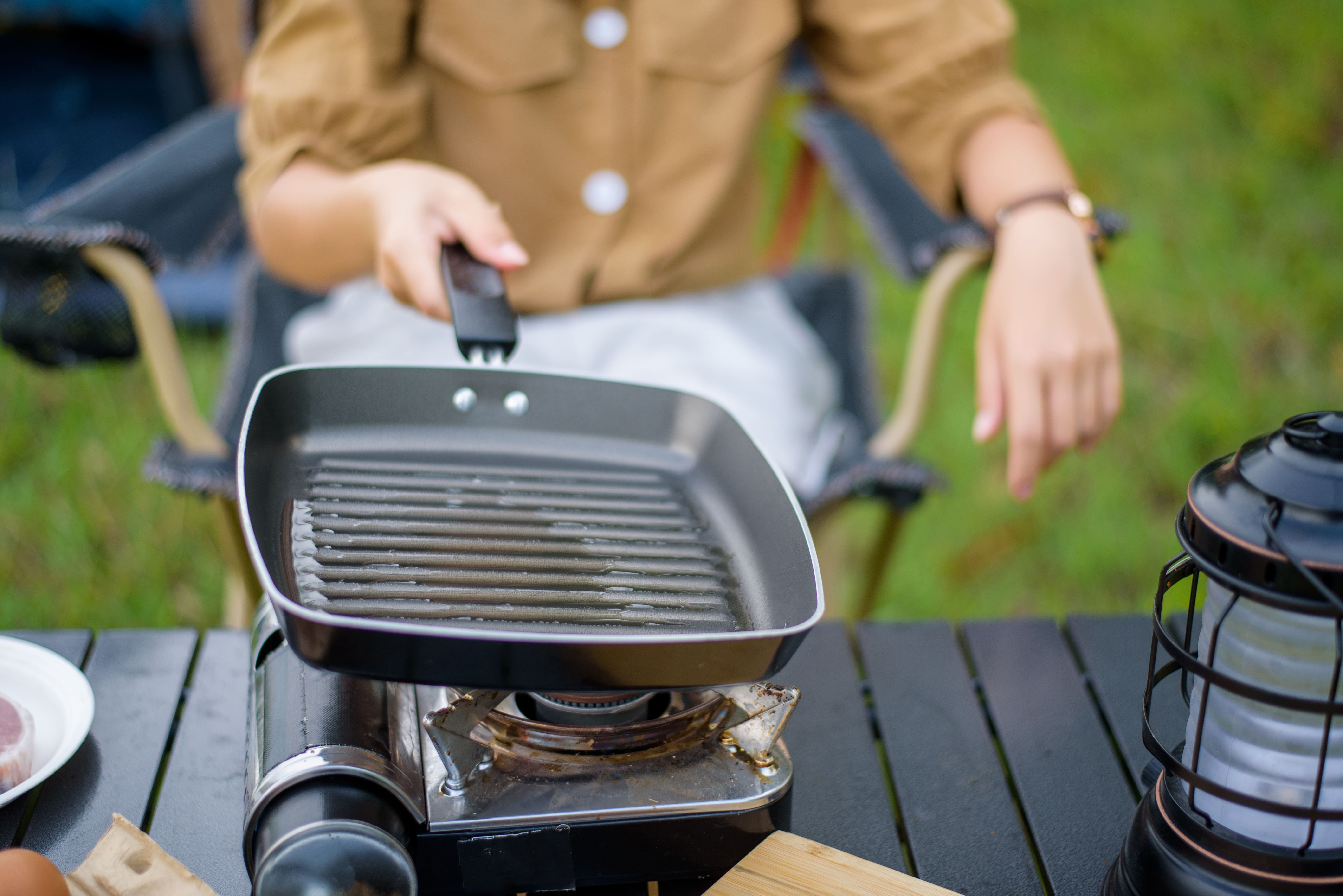 closeup-happy-young-asian-woman-preparing-oil-hot-pan-while-sitting-chair-camping-site-20260528155239.jpg